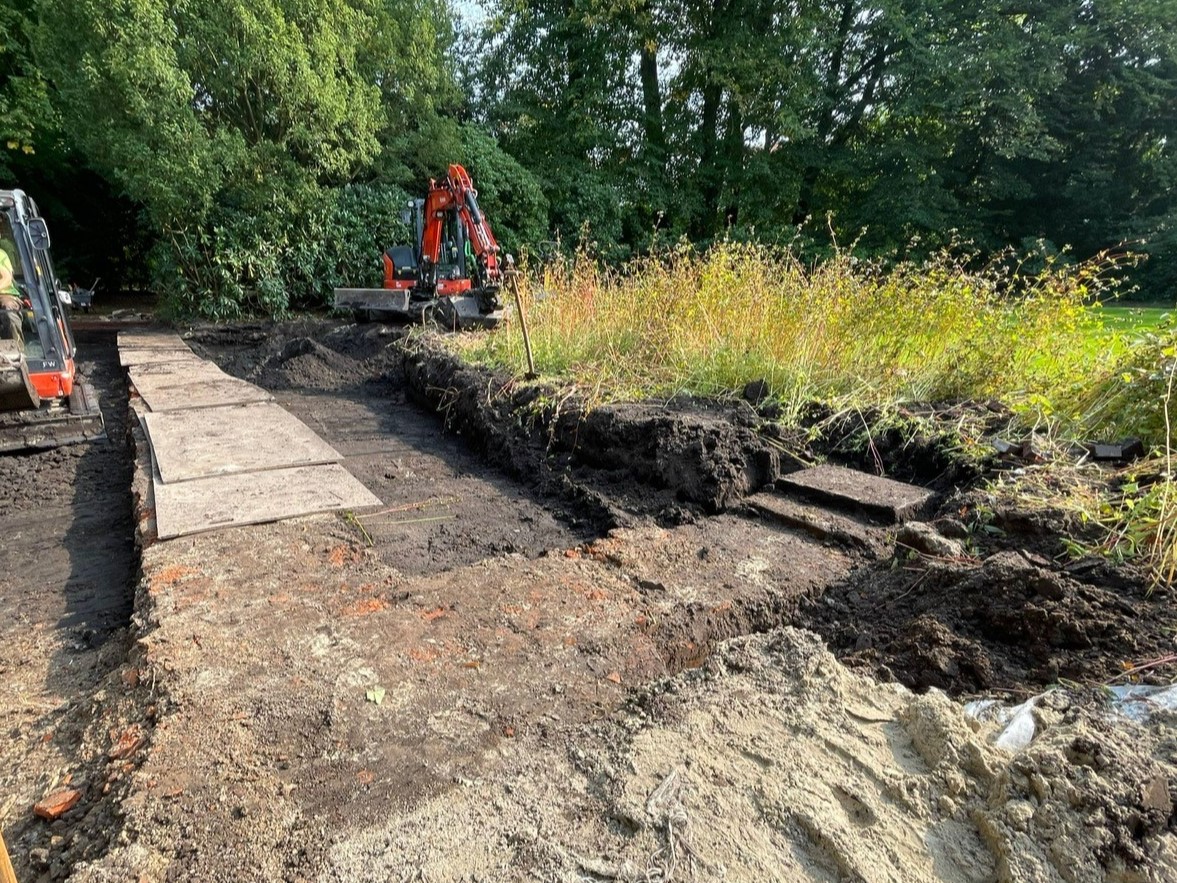 Freigelegte Ziegelsteinmauer in L-Form, drumherum Bagger