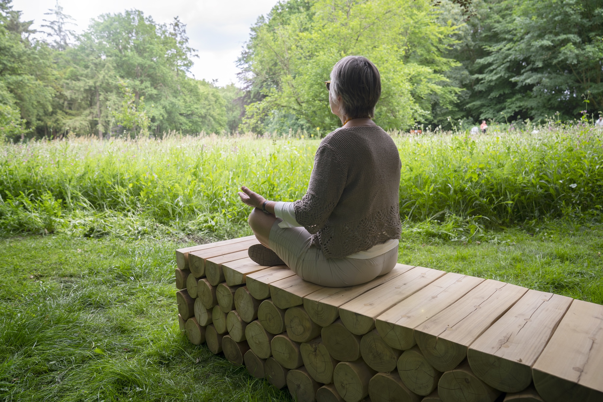 Eine Frau in Meditationspose auf einer Holzbank