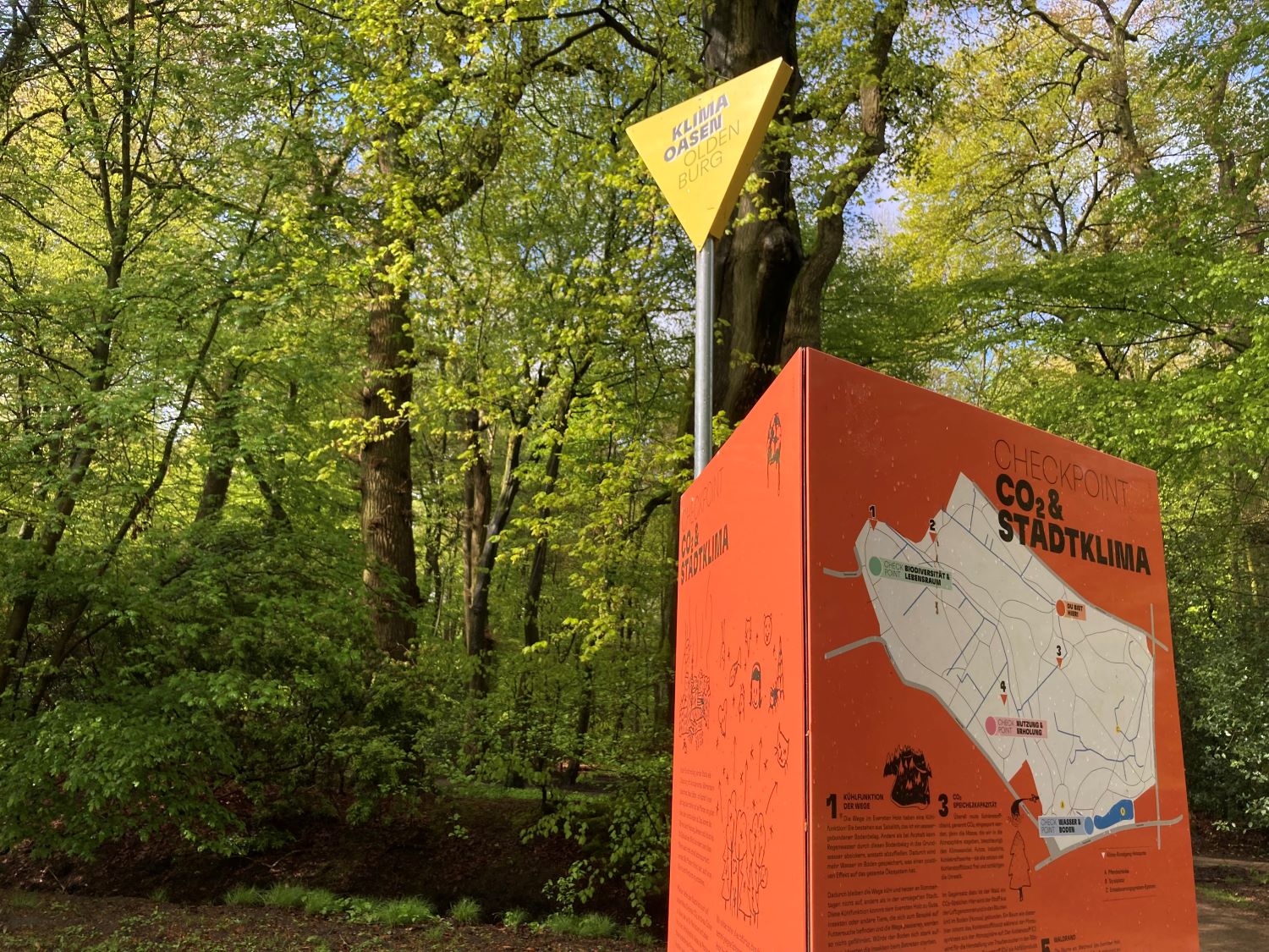 Orange-rotes Checkpoint-Schild des Klimarundgangs vor Bäumen