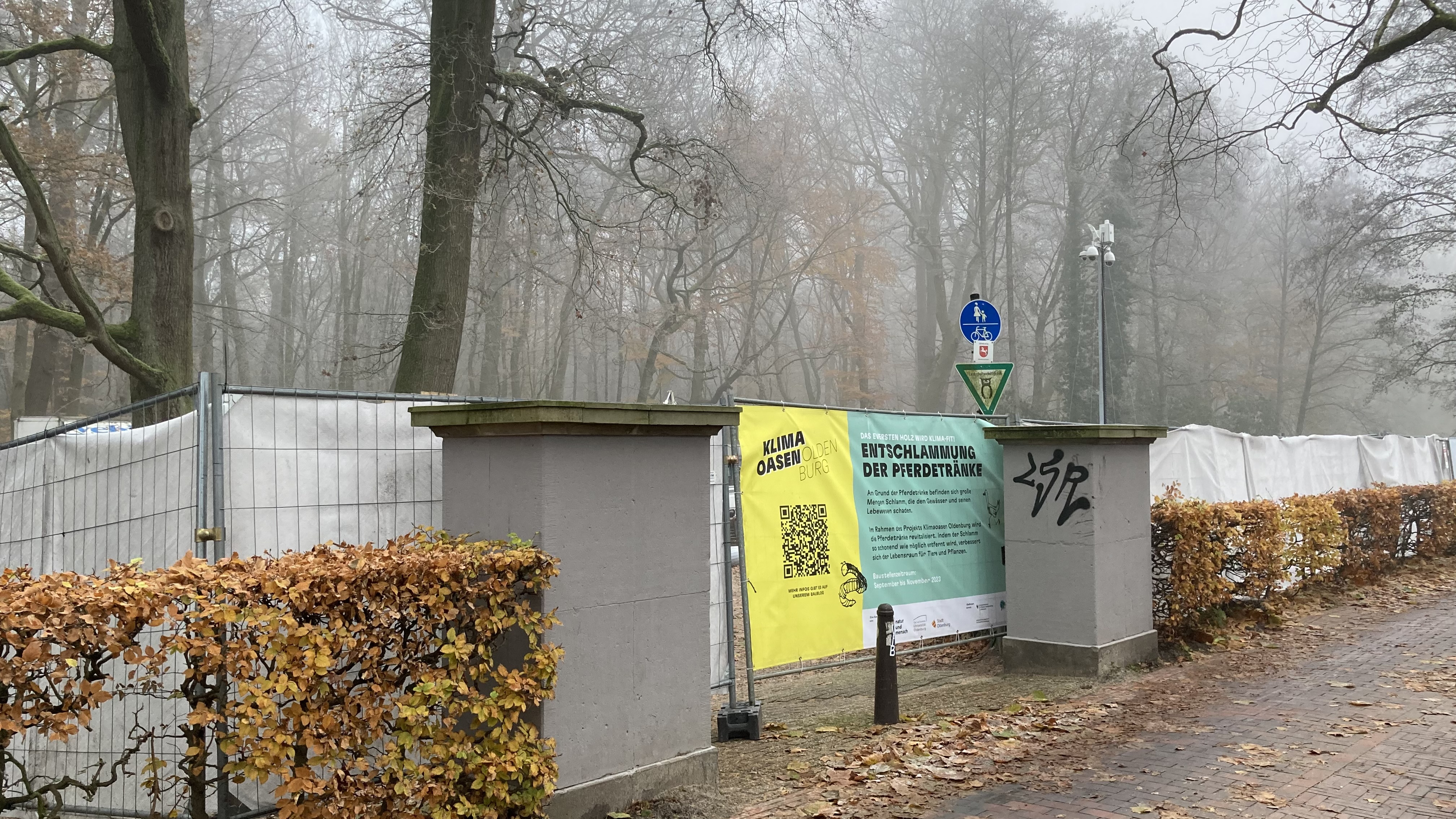 Bauzäune mit Klimaoasen-Banner im Nebel