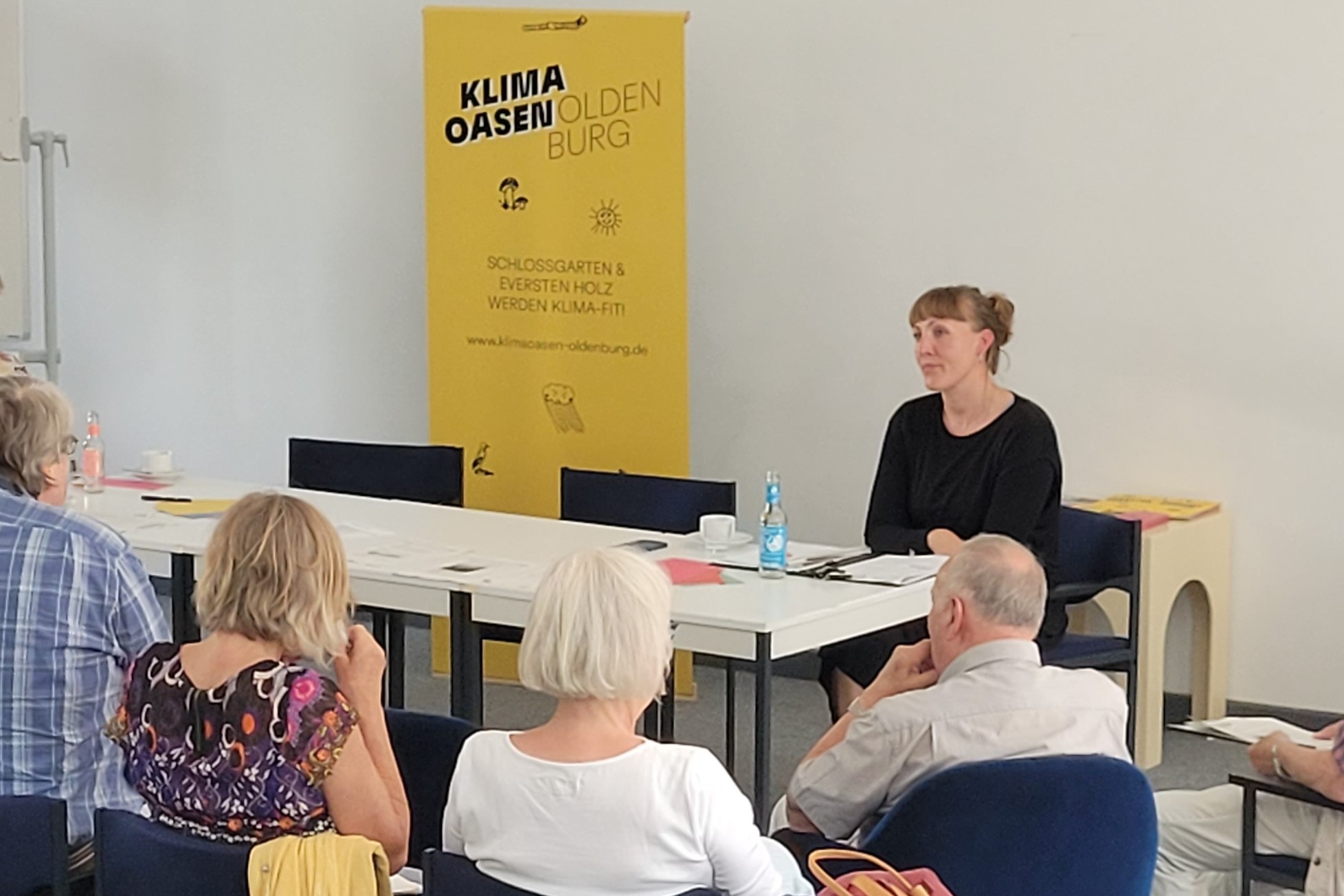 Menschen im Stuhlkreis im Gespräch mit Saskia Benthack, im Hintergrund ein Klimaoasen Banner