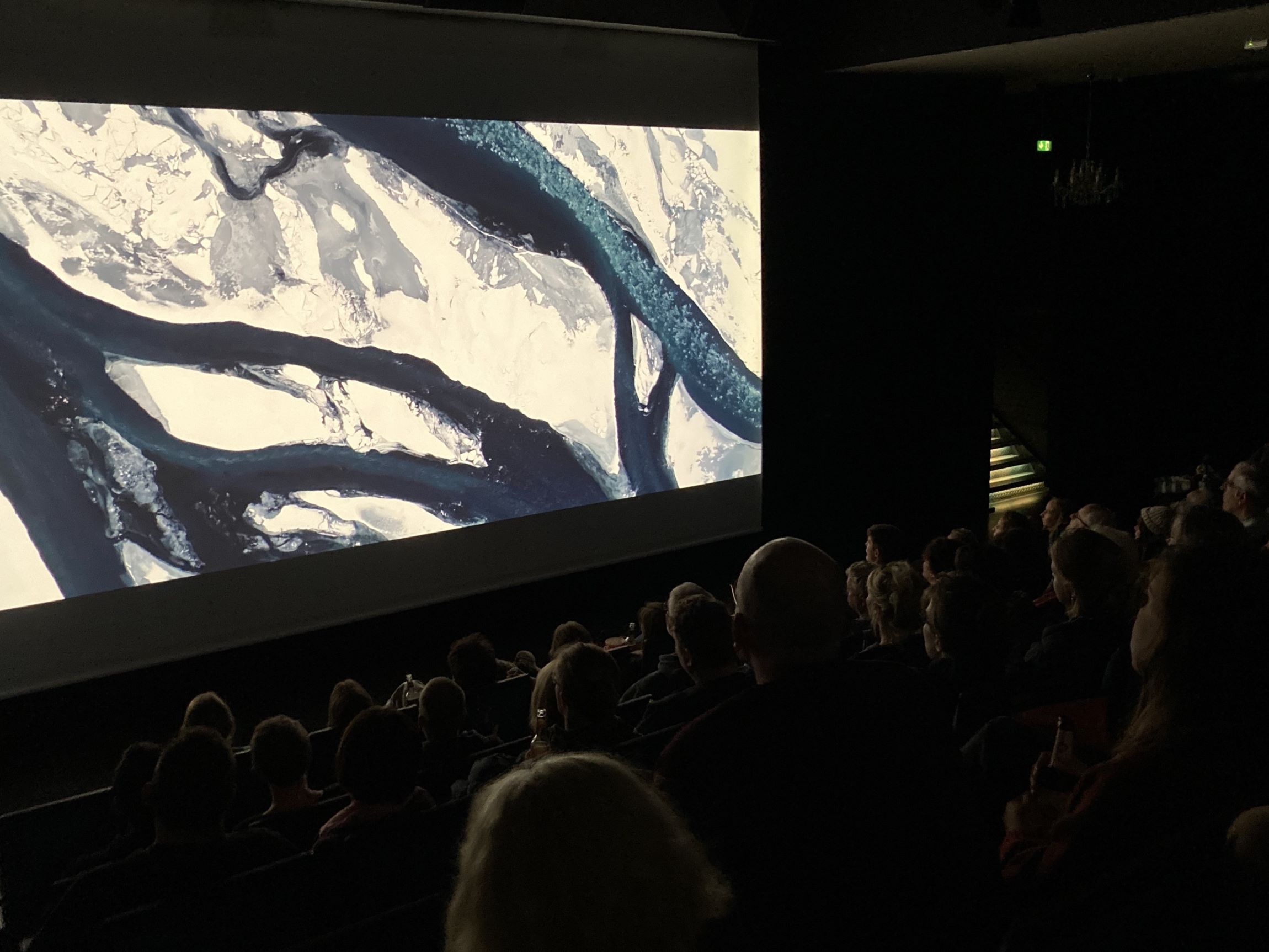 Filmsaal mit Filmleinwand mit einem Fluss der durch Eis fließt. 