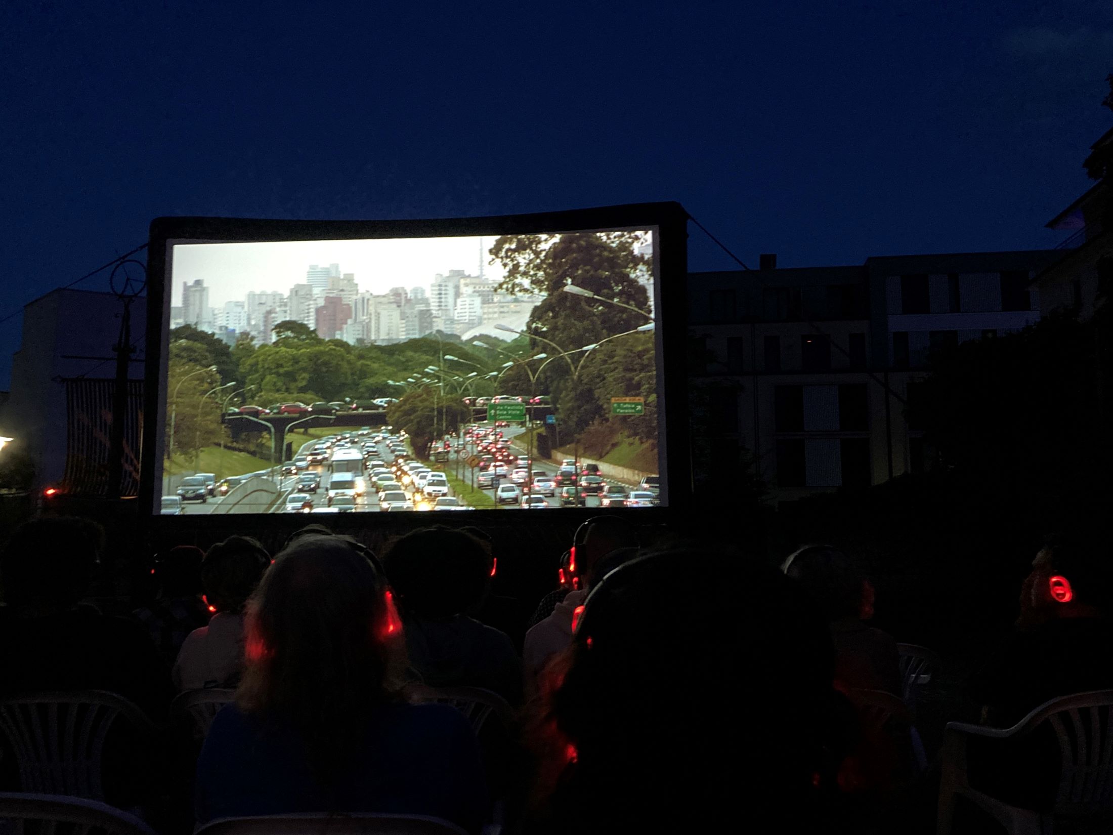 Outdoor Filmleinwand mit leuchtenden Kopfhörern des Publikums