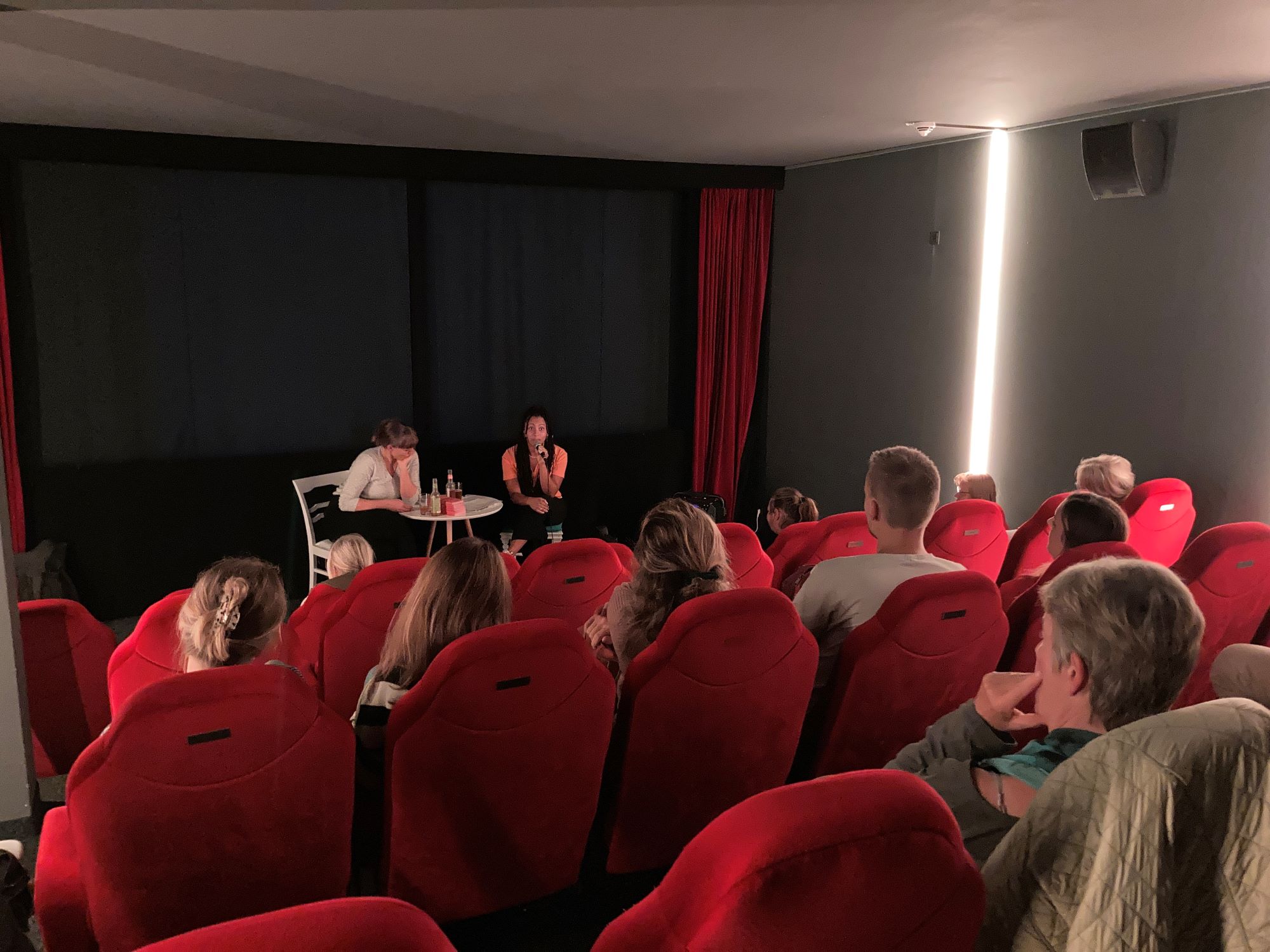 Saskia Benthack und Chioma Ndukwe vor der Kinoleinwand und Filmpublikum